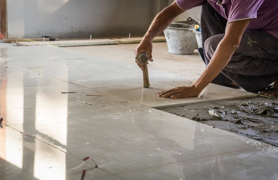 Artisan carreleur professionnel installant du carrelage dans un espace intérieur en construction