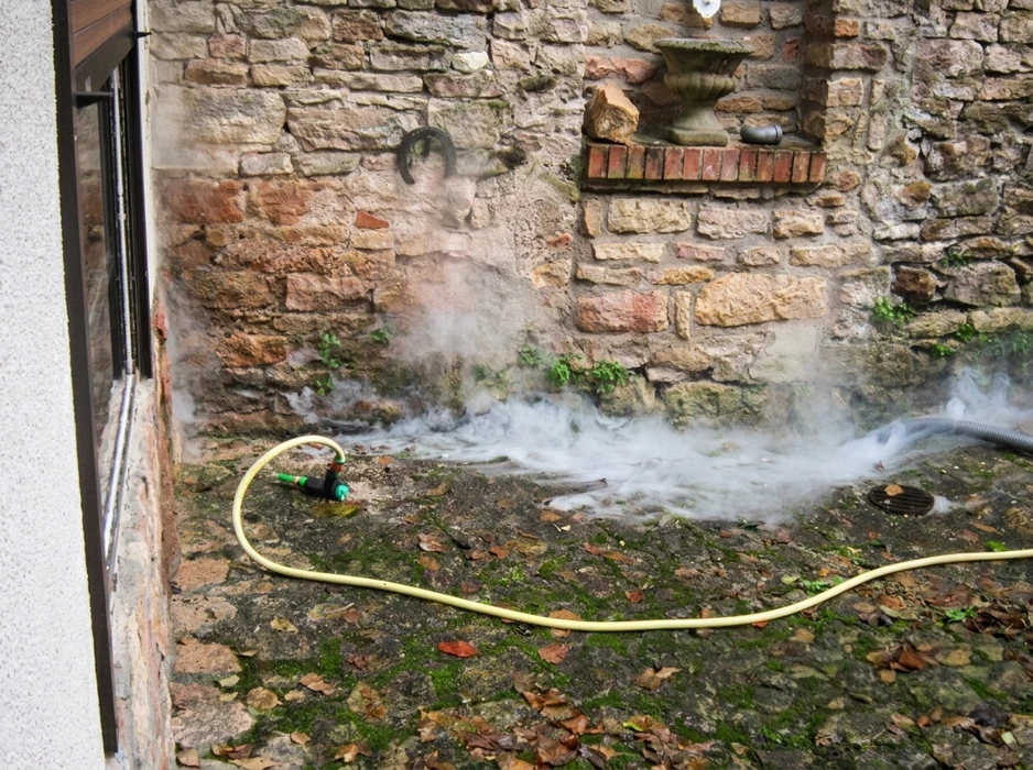 Scène extérieure de fumigation ou désinsectisation au pied d'un mur en pierre ancienne