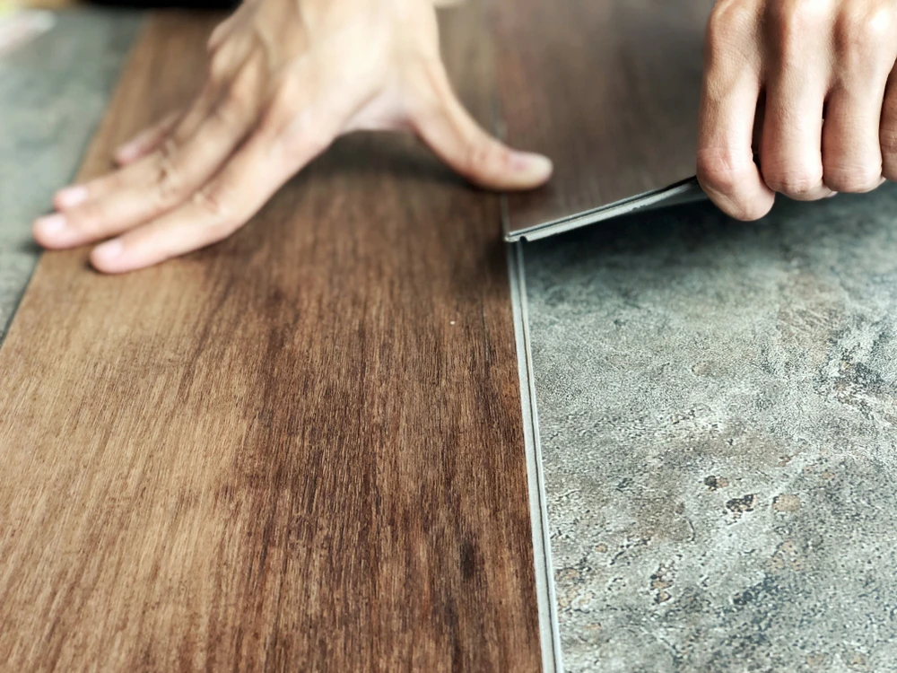 Deux artisans installent un parquet en bois massif dans une pièce aux murs blancs