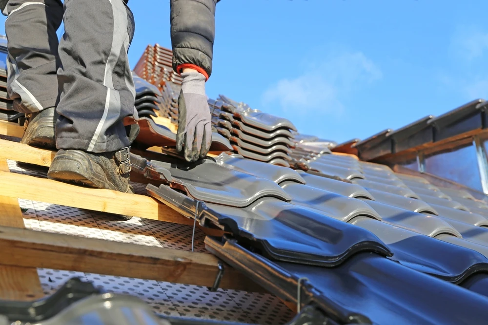 Chantier de couverture en extérieur avec ouvriers installant des tuiles sur toiture